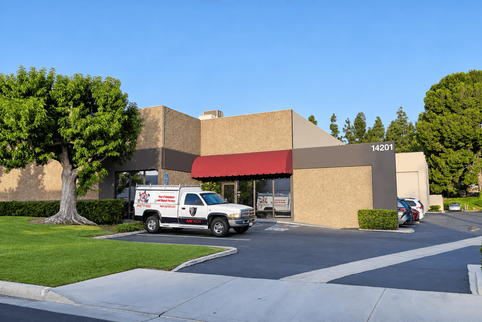 White ASR TECH service truck parked outside a tan commercial building with a red awning.